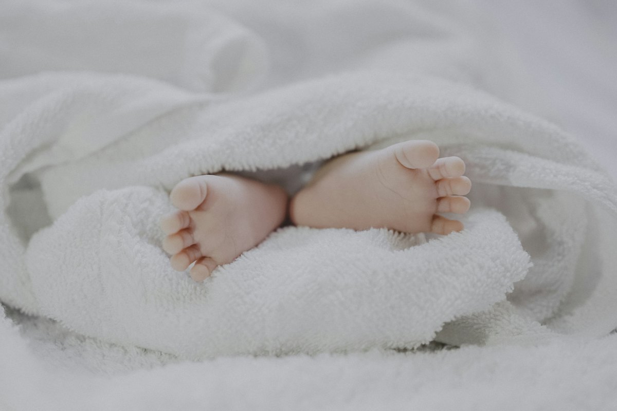 Picioarele unui bebeluș învelite într-o pătură pufoasă albă